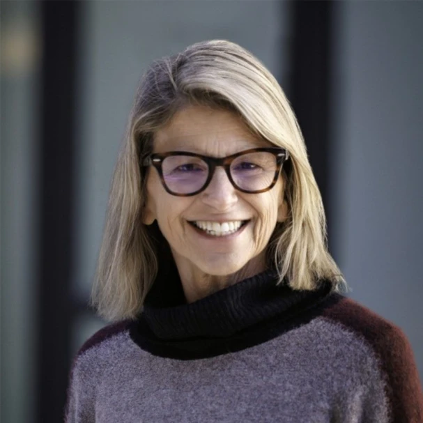 Woman with glasses and gray sweater smiling, professional testimonial portrait