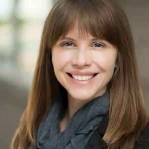 Smiling woman with scarf against a yellow wall, testimonial image