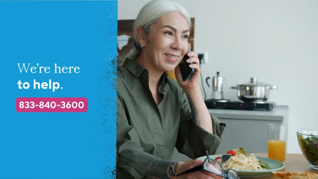 Smiling woman on phone next to branded blue screen reading “We’re here to help”—visual from healthcare microvideo.